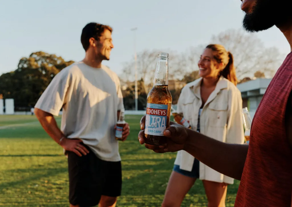 Friends enjoying a Tooheys Ultra Zero Carb beer after playing sports